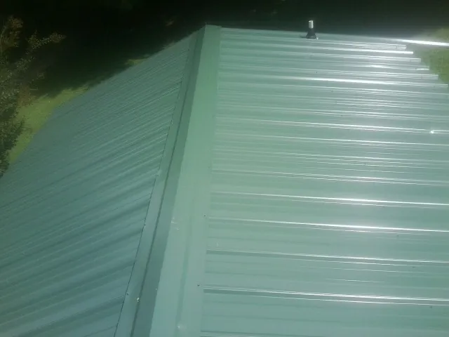 New green metal panels meeting at the ridge of a roof — Flat Roof Repair work by our crew in Brothers