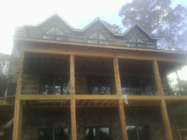 Dormers and porch framing on a large log home under construction — Roof Coating work by our crew in Brothers