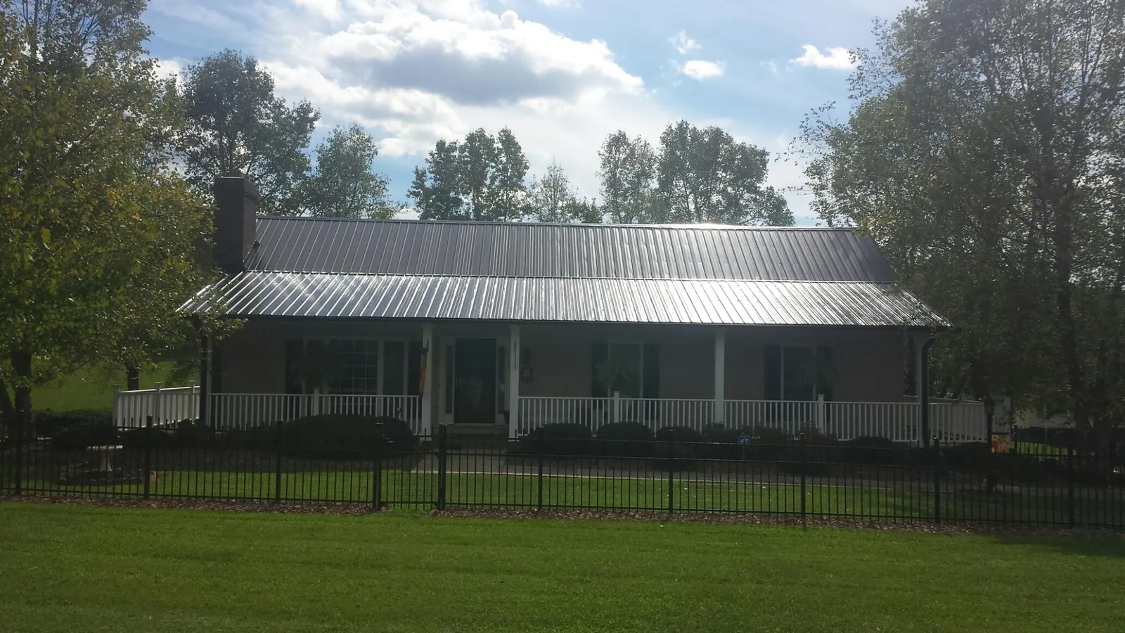 Gray metal roof on a brick ranch with a full width front porch — Gutter Guard Installation work by our crew in Brothers