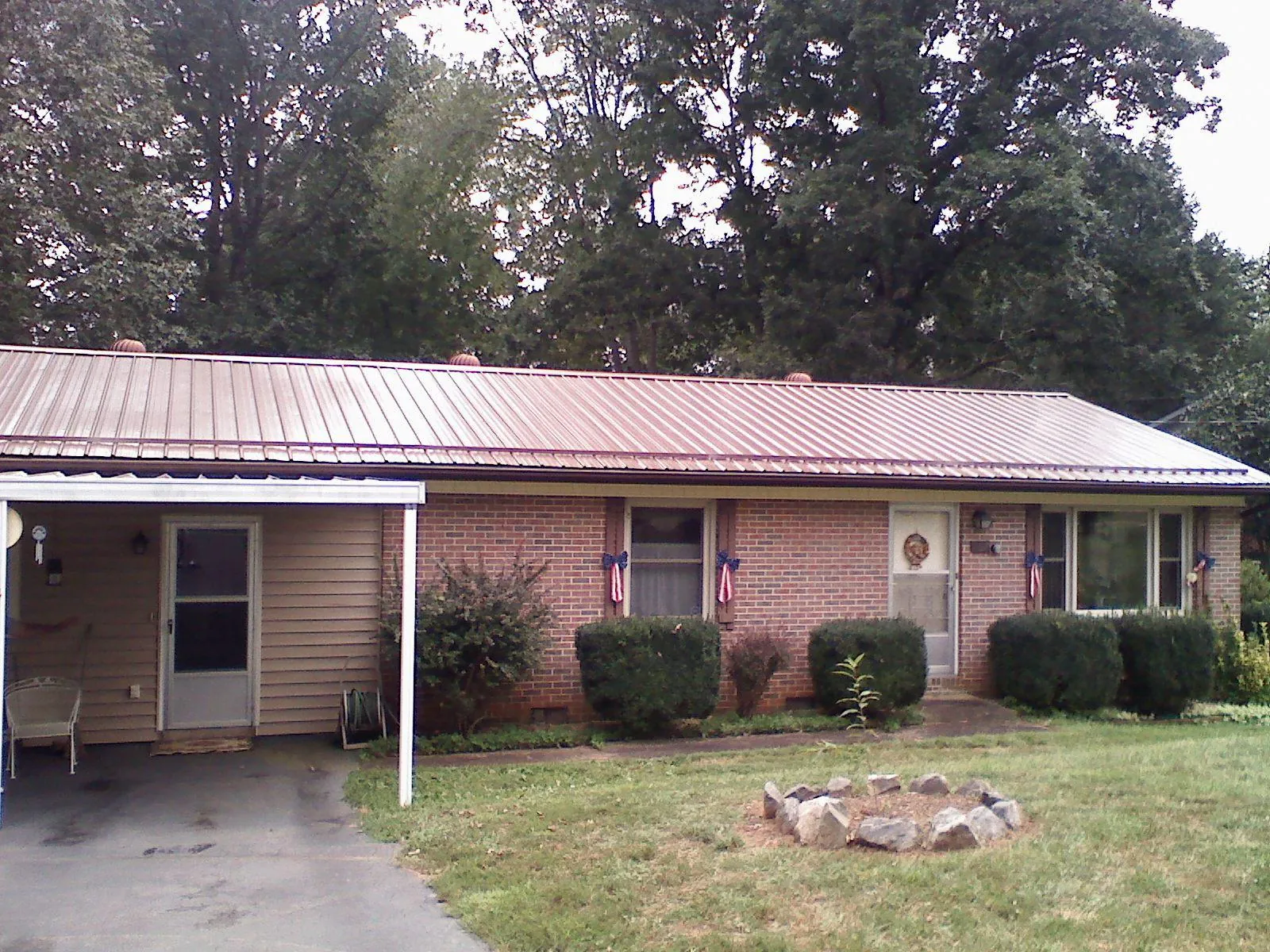 Bronze metal roof and carport on a brick ranch home — Roof Repair work by our crew in Brothers