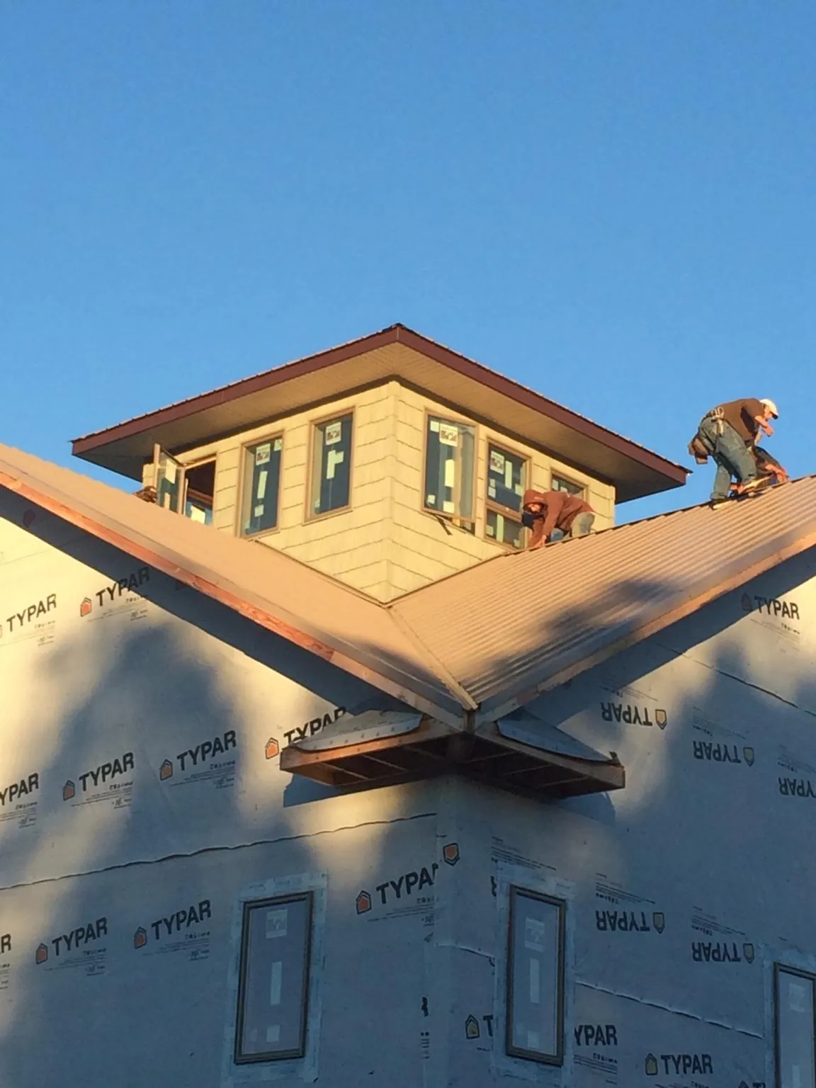 Roofers working around a rooftop cupola on a new metal roof at sunset — Roof Waterproofing in Brothers by Roofing Brothers